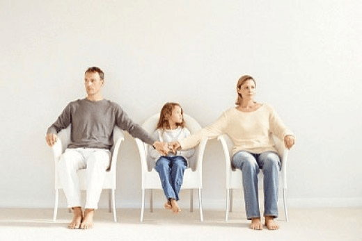 Mom and dad holding hands with daughter in middle while sitting in chairs