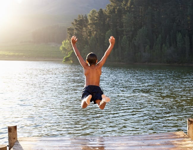 boy jumping off dock into lake