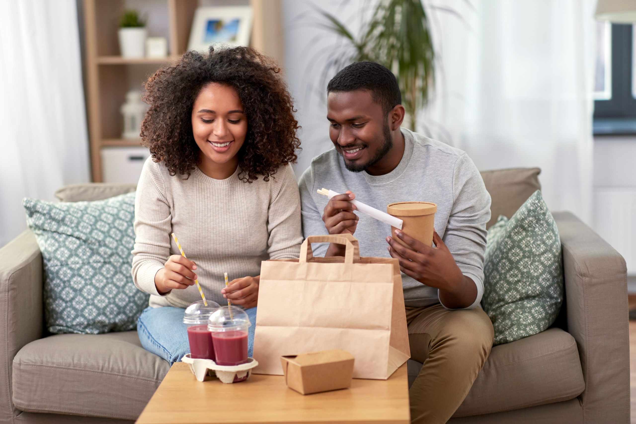 couple enjoying food and smoothies on couch