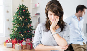 Woman thinking next to husband and Christmas tree